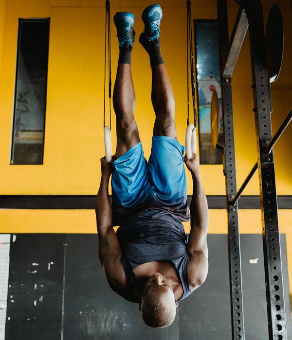 Athletic man performing a controlled strength exercise in a modern, dark gym.