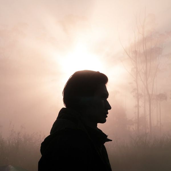 Silhouette of a man in a meditative pose against a sunrise backdrop.